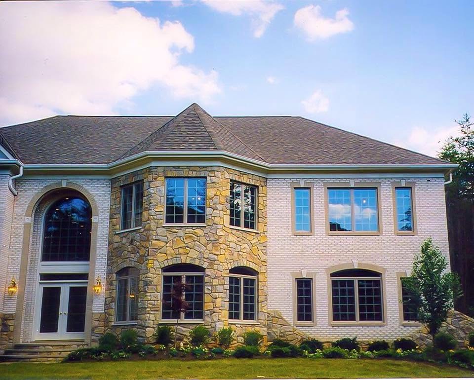 Large custom stone home with arched windows built by Pearl Construction